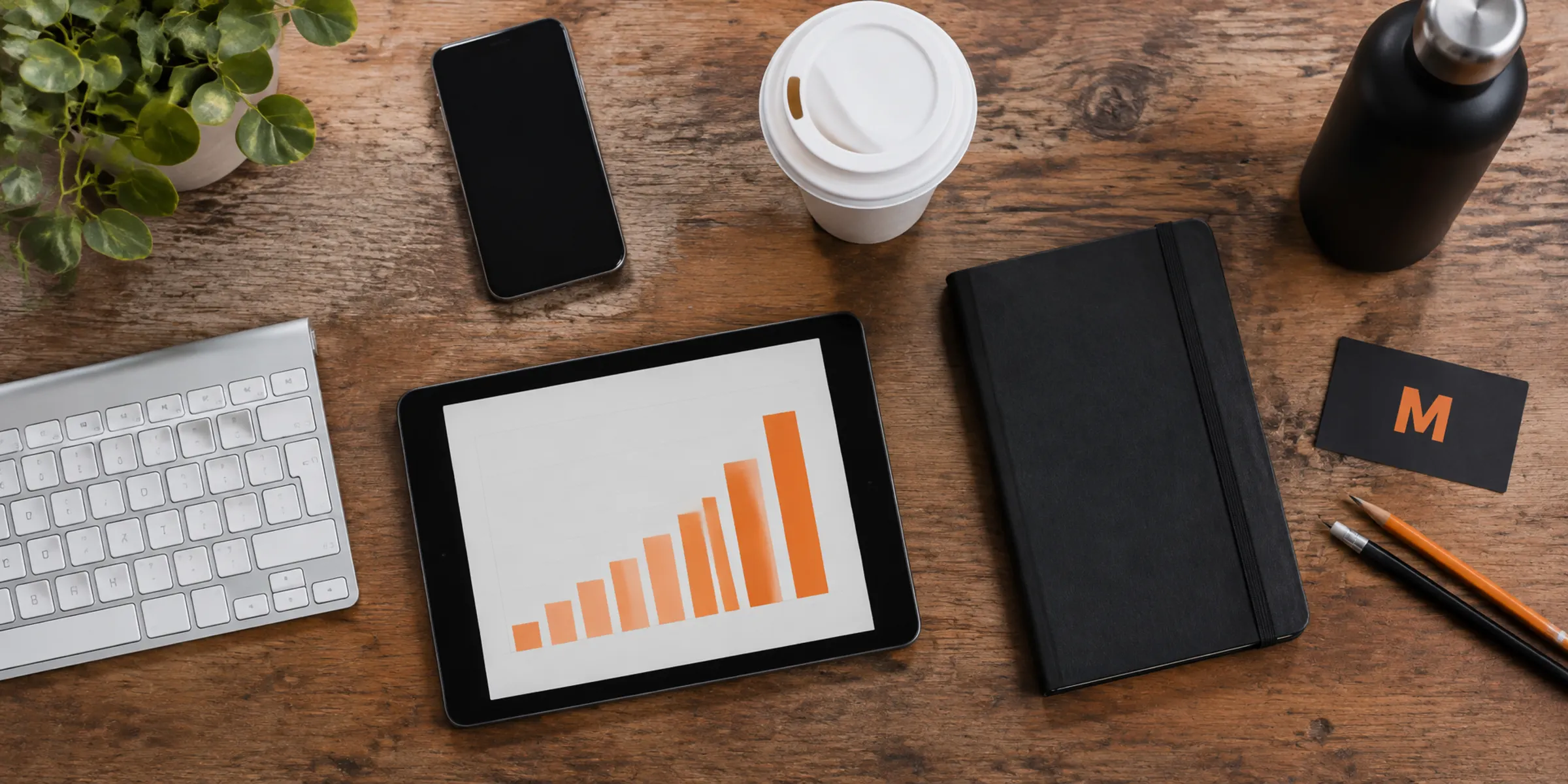 Desk with keyboard, phone, coffee and a tablet showing a bar chart